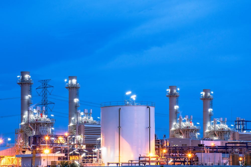 Power generation facility with stacks and storage tank at dusk